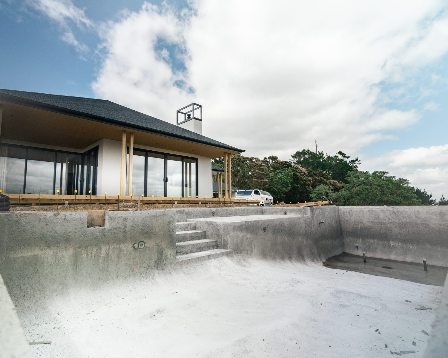 Concrete pool shell with steps formed, a new home with a covered verandah behind