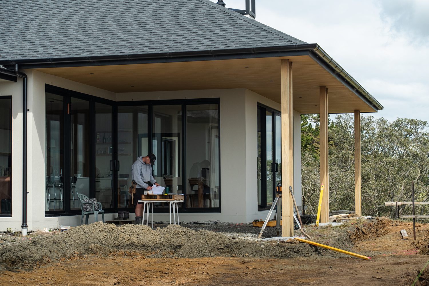 Covered porch of a new home with black window frames, earthworks still under way in front