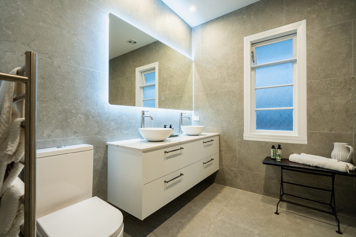 Bathroom with a heated towel rail, toilet, white vanity and a frosted window